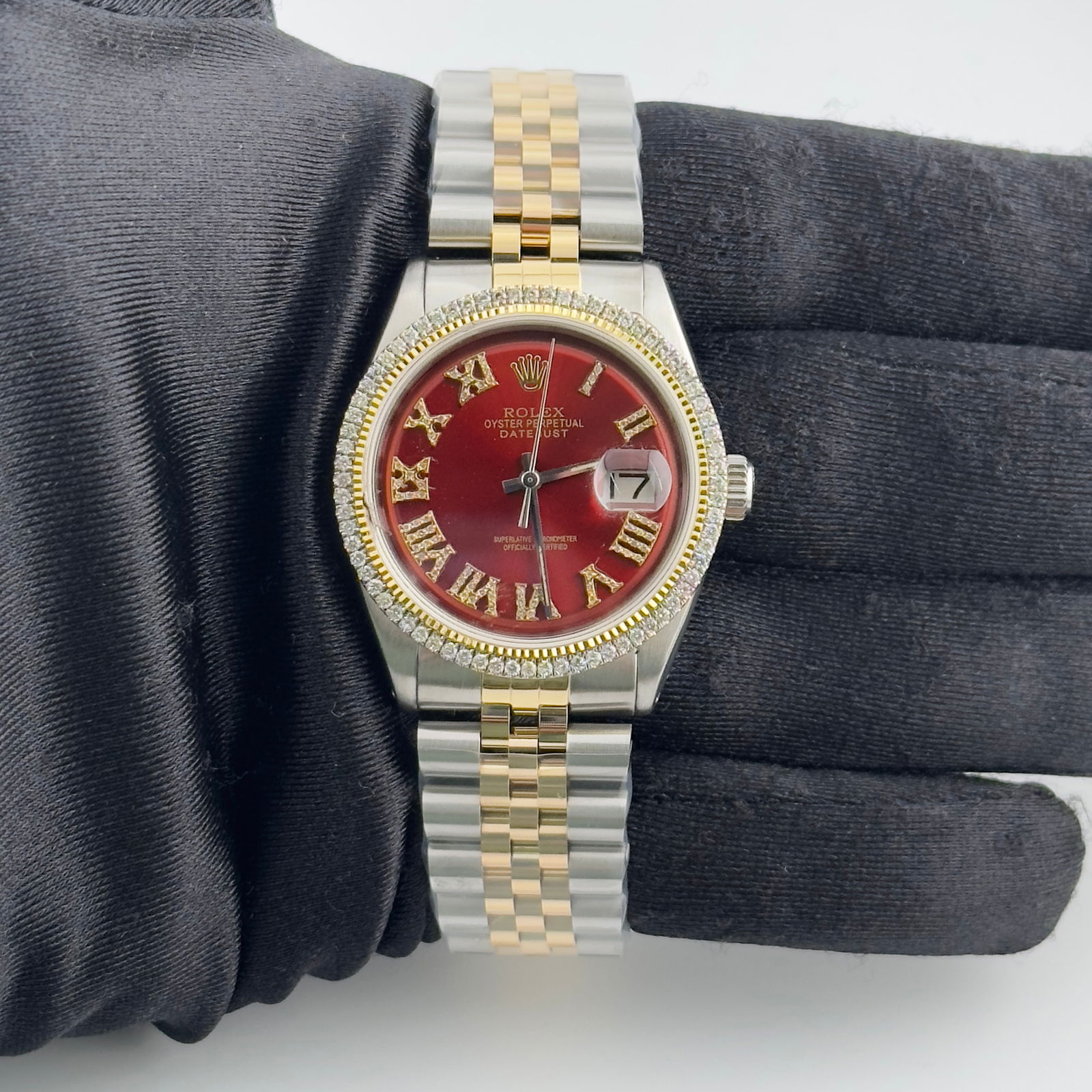 AM Red Roman Diamond Dial Jubilee Rolex Datejust Ref 1601: AM Red Roman Diamond Dial Jubilee Rolex Datejust Ref 1601 This Rolex Datejust features an Aftermarket Red Roman dial adorned with diamond markers and a prong-plated diamond bezel. It is paired with an