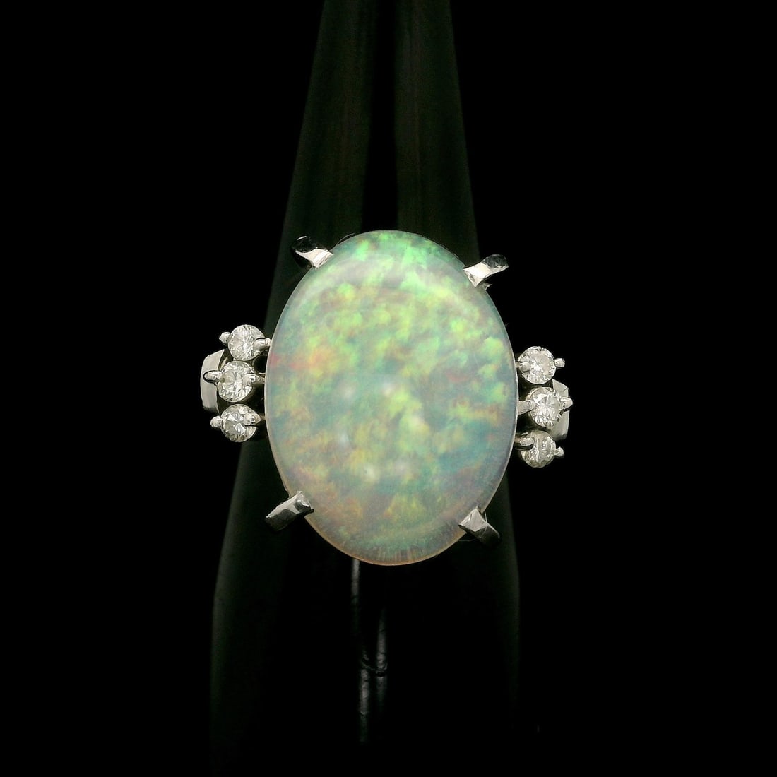 Platinum 5.35ct Oval White Opal Ring with Diamond Accents: Platinum 5.35ct Oval White Opal Ring with Diamond Accents This exquisite cocktail ring features a stunning natural white opal at its center, expertly cut into an oval cabochon shape. The opal showcase