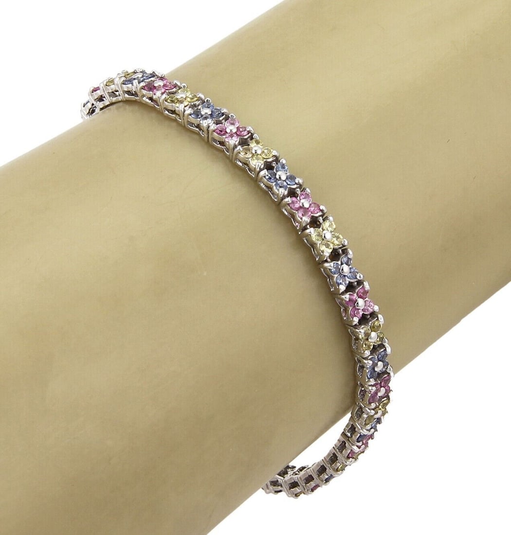 Star Motif 18k White Gold Tennis Bracelet With Multicolor Sapphires: Star Motif 18k White Gold Tennis Bracelet With Multicolor Sapphires This tennis bracelet features pink, blue, and yellow sapphires arranged in a unique star shape design, set in 18k white gold. The br
