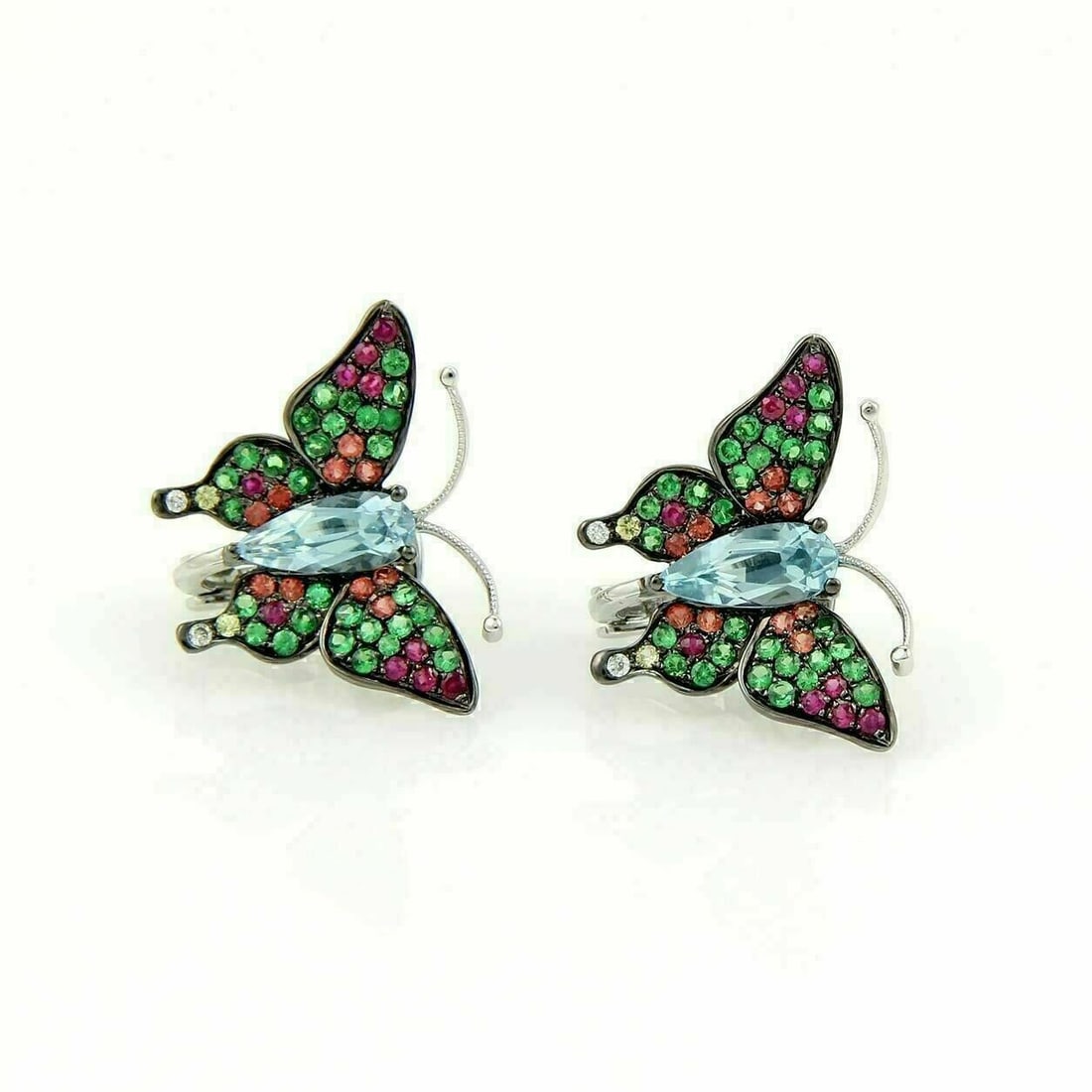 Huggie Earrings in 18k Gold with Blue Topaz Sapphires Tsavorite Butterfly Motif: Huggie Earrings in 18k Gold with Blue Topaz Sapphires Tsavorite Butterfly Motif These butterfly earrings are crafted from 18k white gold in a huggie style for a close, comfortable fit. The earrings ar