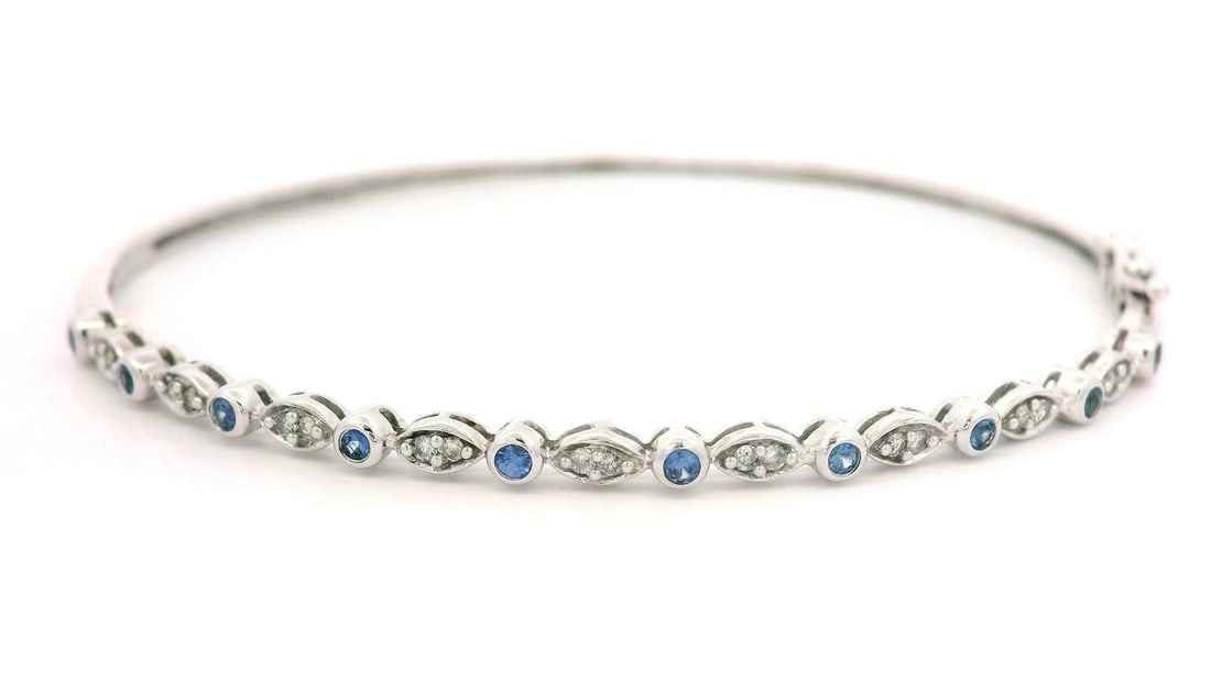14k White Gold Hinged Bangle Bracelet with Sapphire and Diamond Accents: 14k White Gold Hinged Bangle Bracelet with Sapphire and Diamond Accents This exquisite 14k White Gold Hinged Bangle Bracelet features a delicate design enhanced by natural sapphires and diamonds. The