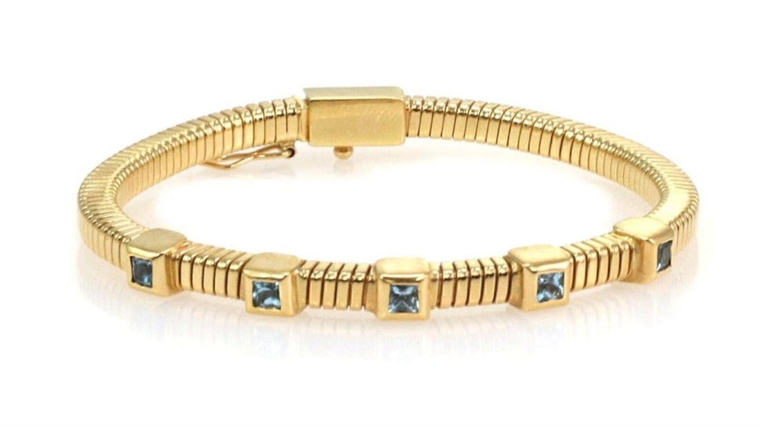18k Yellow Gold Bangle Bracelet with Square Blue Topaz Gemstones: 18k Yellow Gold Bangle Bracelet with Square Blue Topaz Gemstones This vintage bracelet features square cut blue topaz gemstones set in a flexible 18k yellow gold bangle design. The combination of