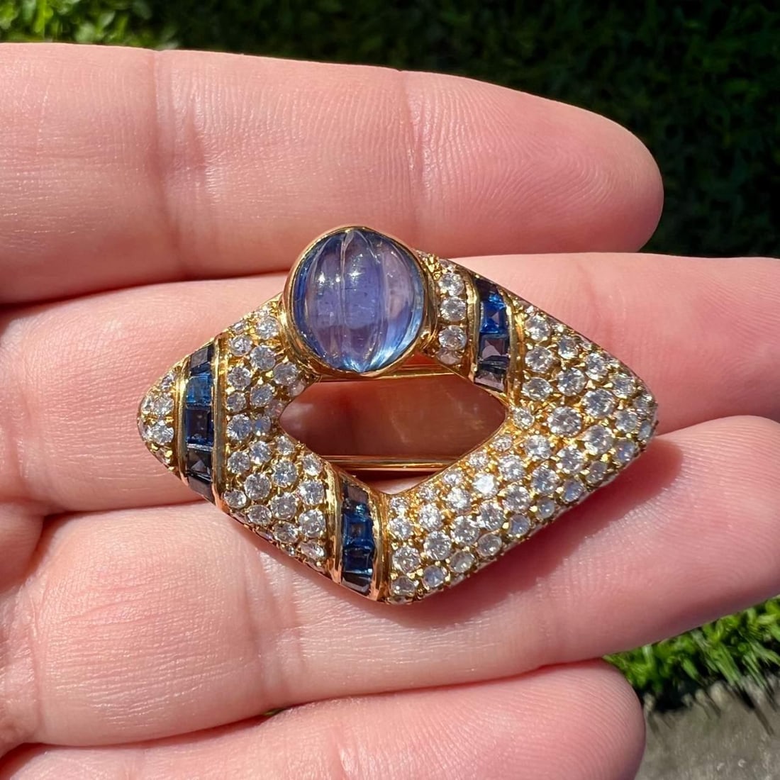 Elegant 18K Yellow Gold Brooch with Carved Sapphire Diamonds: Elegant 18K Yellow Gold Brooch with Carved Sapphire Diamonds This exquisite 18K Yellow Gold Brooch features a stunning carved sapphire weighing approximately 4.00 Ct, complemented by 13 additional sap