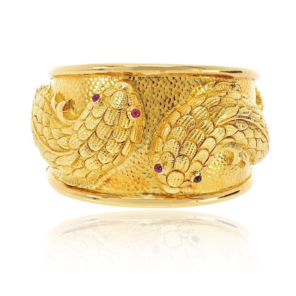 Double Fish Bracelet in 18K Yellow Gold with Ruby Eyes by David Webb: Double Fish Bracelet in 18K Yellow Gold with Ruby Eyes by David Webb This David Webb bracelet features a double fish design crafted in 18K yellow gold, accented with ruby eyes. The piece is signed by