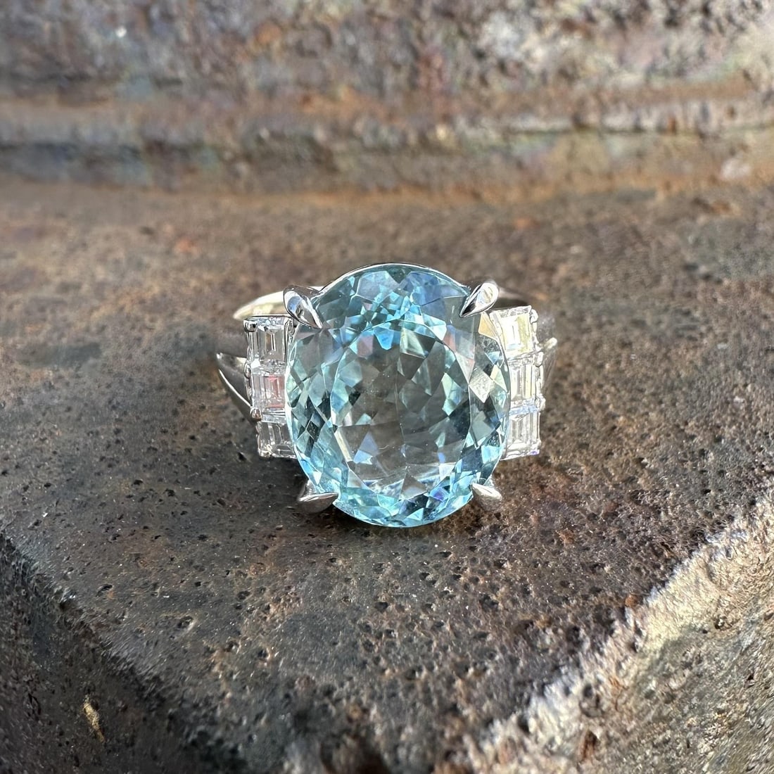 Platinum Ring with 4.84ct Oval Aquamarine and Step Cut Diamond Accents: Platinum Ring with 4.84ct Oval Aquamarine and Step Cut Diamond Accents This classic cocktail ring features a natural oval brilliant cut aquamarine weighing 4.50 carats, displaying a vibrant blue color