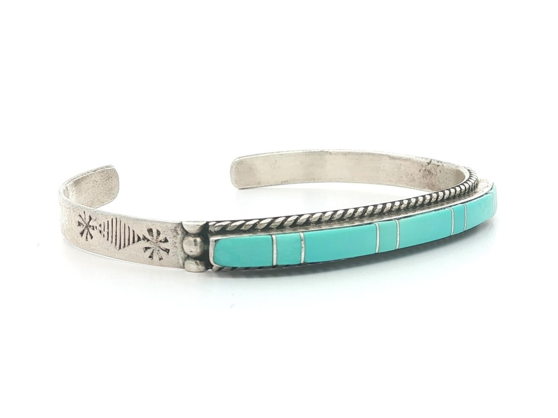 Sterling Silver Turquoise Inlay Cuff Bangle with Repose Detailing: Sterling Silver Turquoise Inlay Cuff Bangle with Repose Detailing This Navajo cuff bangle bracelet features a narrow design crafted from .925 sterling silver with traditional repose work. It is set wi