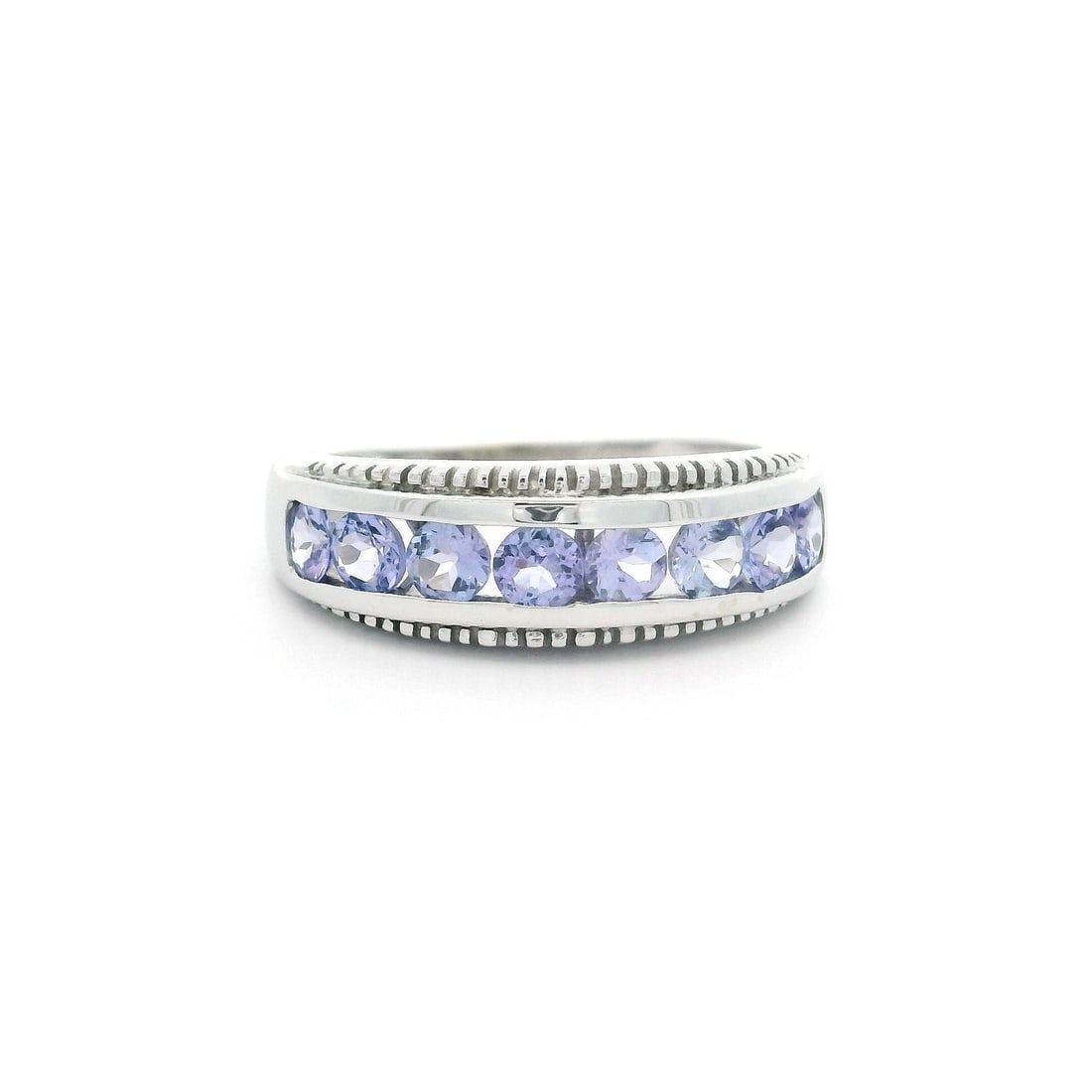 10K White Gold Milgrain Band Ring with Tanzanite Channel Set: 10K White Gold Milgrain Band Ring with Tanzanite Channel Set This exquisite 10k White Gold Channel Set Tanzanite Band Ring showcases a classic milgrain design. The ring features eight natural genuine