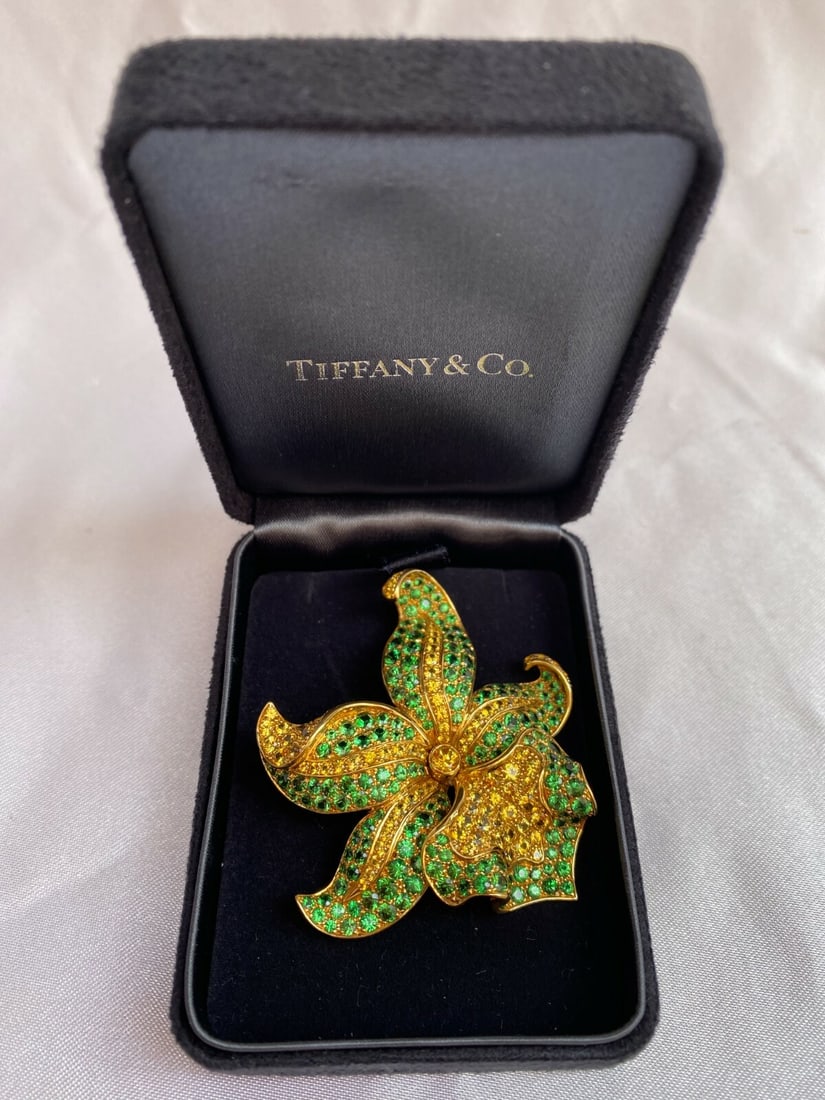 Tiffany & Co 18K Gold Diamond Tsavorite Garnet Yellow Sapphire Orchid Brooch Limited Edition: Tiffany & Co 18K Gold Diamond Tsavorite Garnet Yellow Sapphire Orchid Brooch Limited Edition This exquisite Tiffany & Co. brooch features a stunning orchid design crafted from 18K yellow gold, adorned