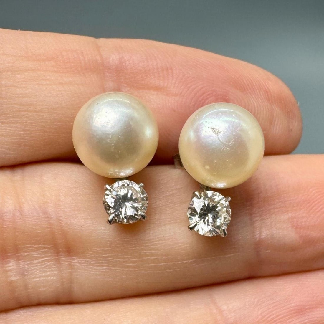 Yellow Gold Earrings with Pearl and Diamond Accents in 14K: Yellow Gold Earrings with Pearl and Diamond Accents in 14K These earrings feature 14K yellow gold settings adorned with pearls and two diamonds totaling approximately 0.80 carats. The diamonds are gra