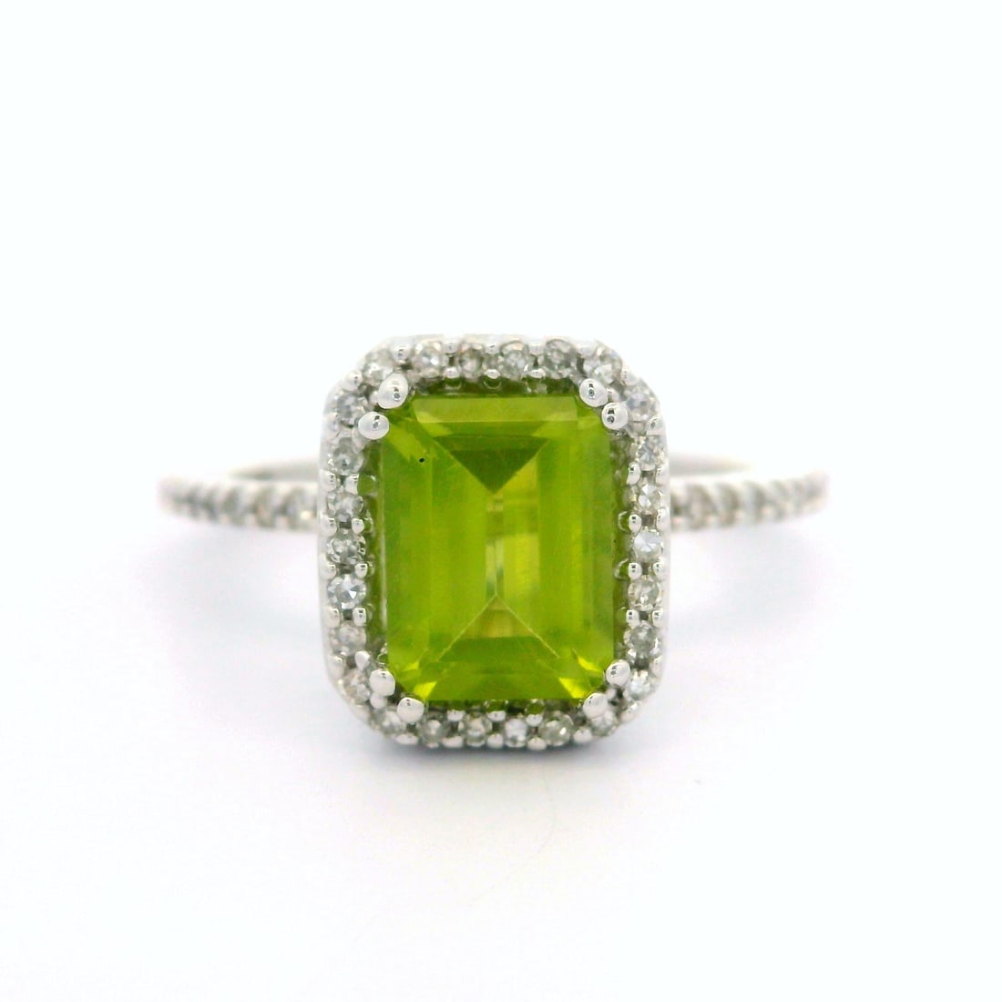 Modern 14k White Gold Peridot Diamond Halo Solitaire Ring: Modern 14k White Gold Peridot Diamond Halo Solitaire Ring This stunning cocktail ring features a modern design crafted from 14k white gold, showcasing a beautiful step cut peridot at its center. The v