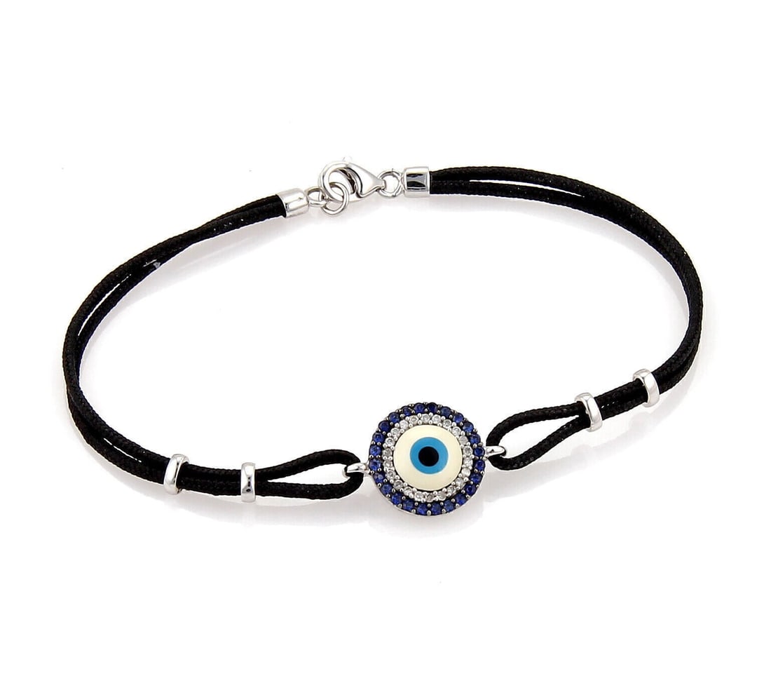 Cord Bracelet with 18k White Gold Evil Eye Sapphire and Diamond Charm: Cord Bracelet with 18k White Gold Evil Eye Sapphire and Diamond Charm This 18k white gold cord bracelet features an evil eye charm adorned with 0.10ct of diamonds and 0.20ct of sapphires. The bracelet