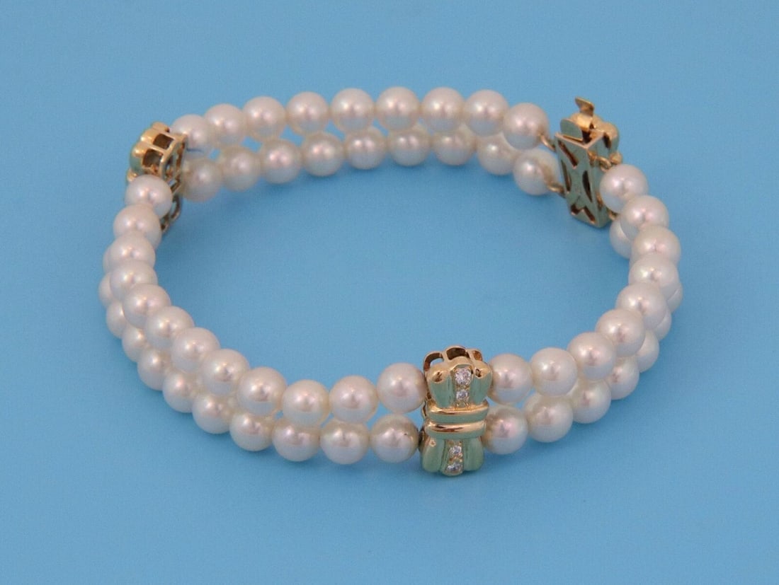 Two Strand Cultured Pearl Diamond Bracelet in 18k Gold Bow Motif by Mikimoto: Two Strand Cultured Pearl Diamond Bracelet in 18k Gold Bow Motif by Mikimoto This authentic Mikimoto bracelet features two strands of lustrous Japanese cultured pearls set in solid 18k yellow gold. Th