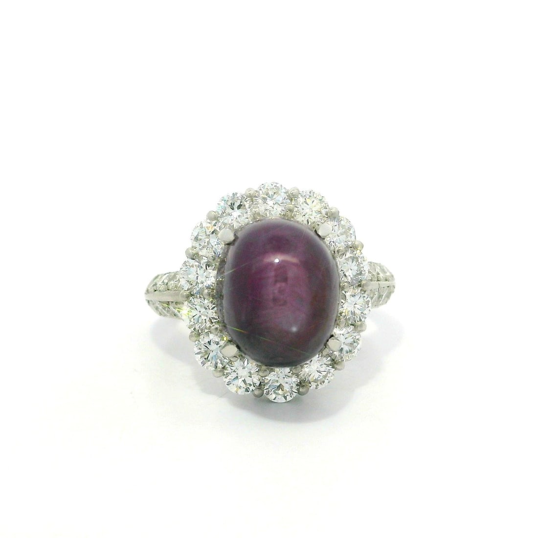 Platinum 12.62ct Star Ruby Ring with Diamond Halo: Platinum 12.62ct Star Ruby Ring with Diamond Halo This stunning cocktail ring features a large oval cabochon star ruby, showcasing its natural purplish-red hue without any heat treatment. The star rub