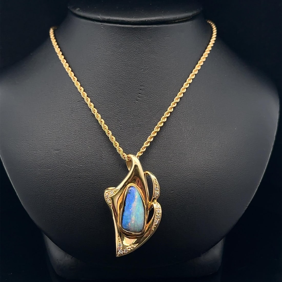 18k Yellow Gold Boulder Opal Diamond Pendant Necklace with Rope Chain: 18k Yellow Gold Boulder Opal Diamond Pendant Necklace with Rope Chain This exquisite pendant necklace features a stunning freeform boulder opal, showcasing a captivating blue base enhanced by a remark
