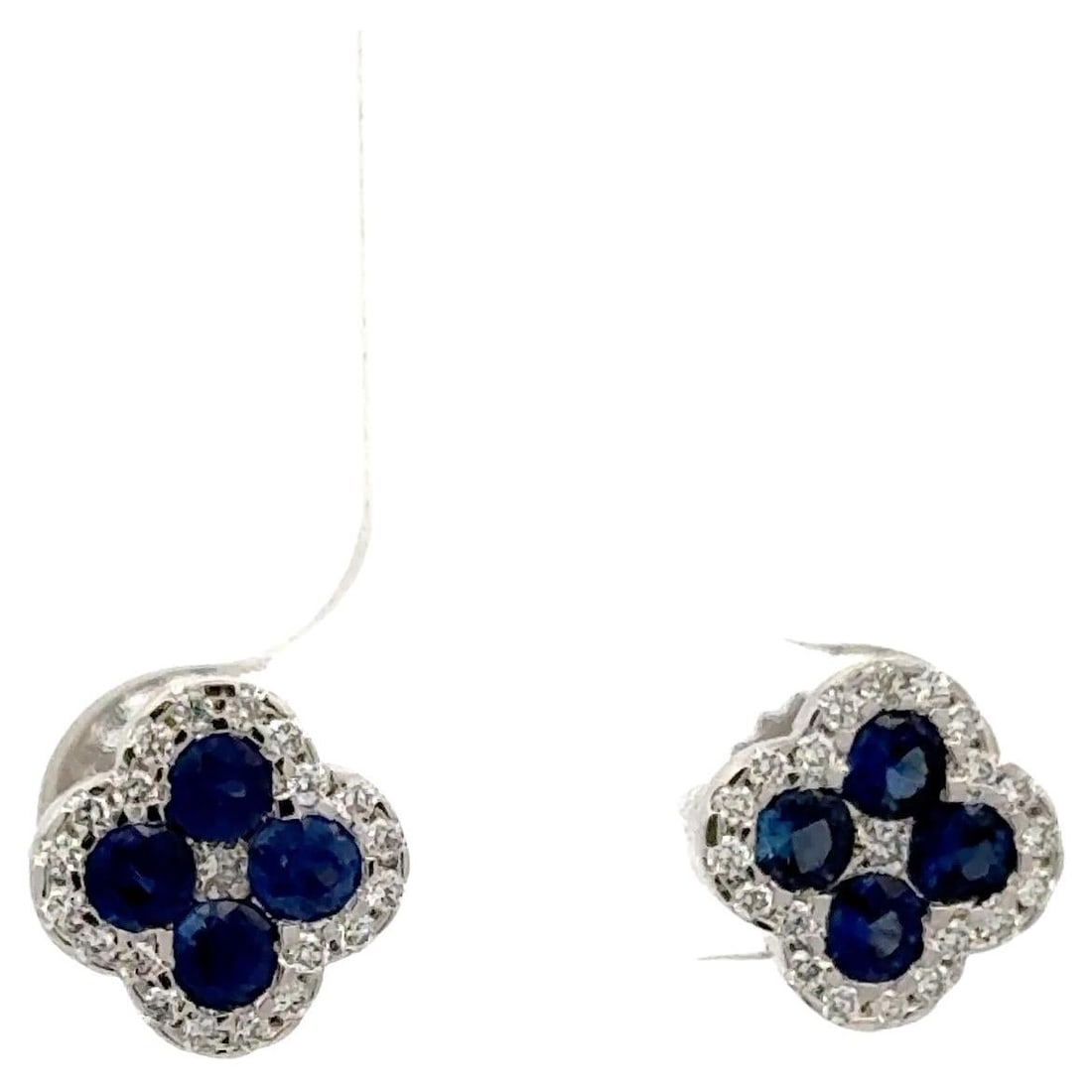 Four-Petal Clover Stud Earrings in 18K White Gold with Sapphire and Diamond Halo: Four-Petal Clover Stud Earrings in 18K White Gold with Sapphire and Diamond Halo These elegant stud earrings are crafted from 18K white gold and feature a four-petal clover motif. Each earring is ador