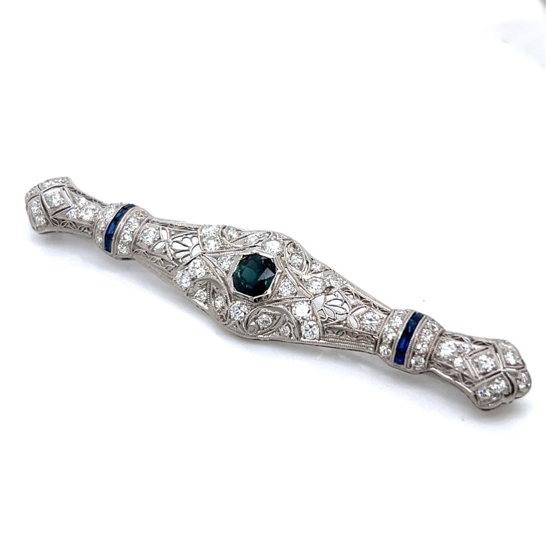 Art Deco Platinum Brooch with 0.90 Ct Sapphire and 56 Diamonds: Art Deco Platinum Brooch with 0.90 Ct Sapphire and 56 Diamonds This exquisite Art Deco brooch is crafted in platinum, showcasing a stunning central sapphire and an array of sparkling diamonds. The cen