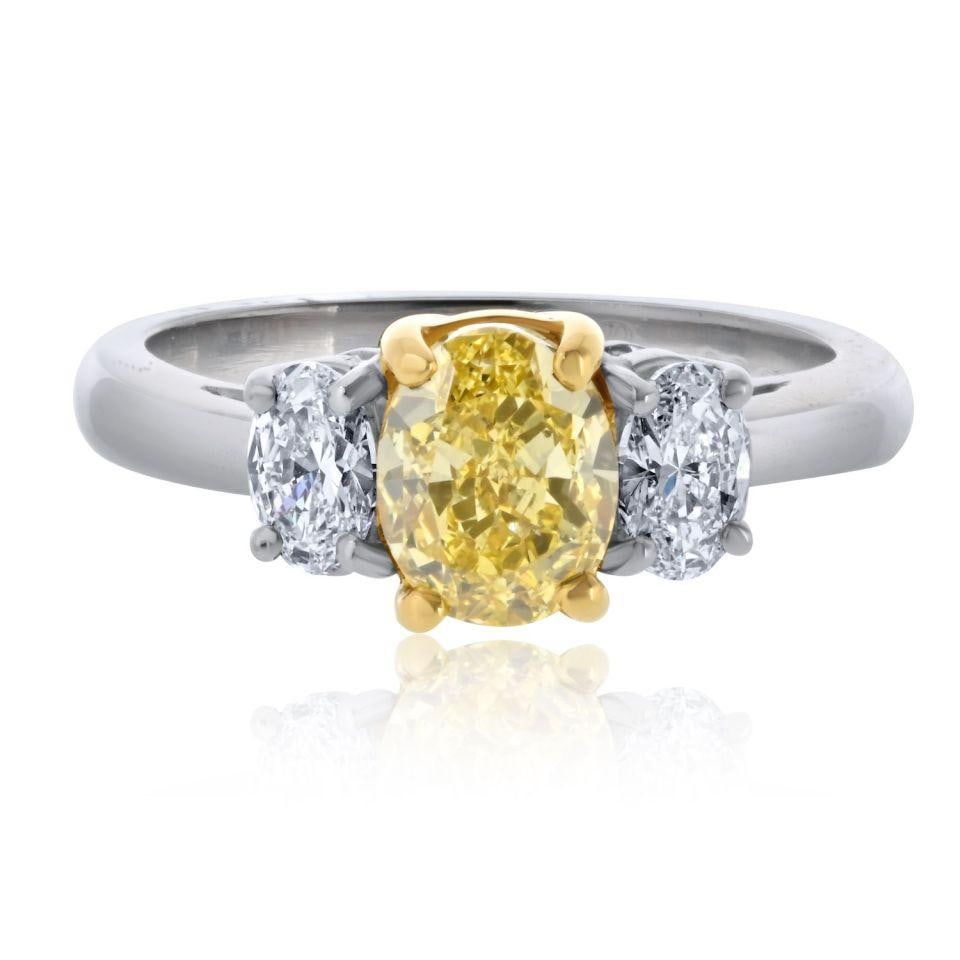 Fancy Intense Yellow Oval Diamond Ring with White Side Ovals in Platinum and Gold: Fancy Intense Yellow Oval Diamond Ring with White Side Ovals in Platinum and Gold This exquisite Fancy Yellow Ring showcases a stunning combination of Platinum and 18K Yellow Gold, weighing 6.8 grams.