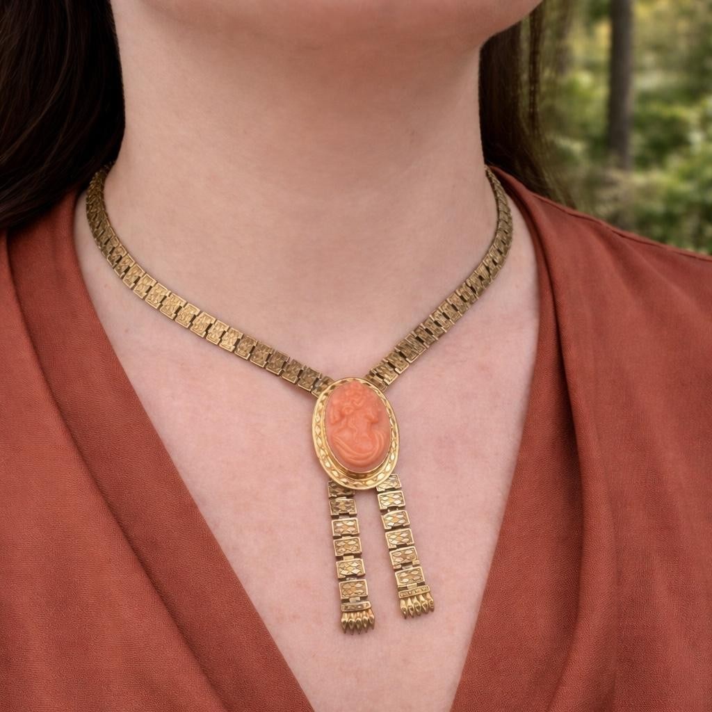 Victorian Era Yellow Gold Necklace With Carved Coral Cameo Tassel Pendant: Victorian Era Yellow Gold Necklace With Carved Coral Cameo Tassel Pendant This antique Victorian necklace features a central carved oval salmon pink coral cameo, bezel-set in solid yellow gold. The de