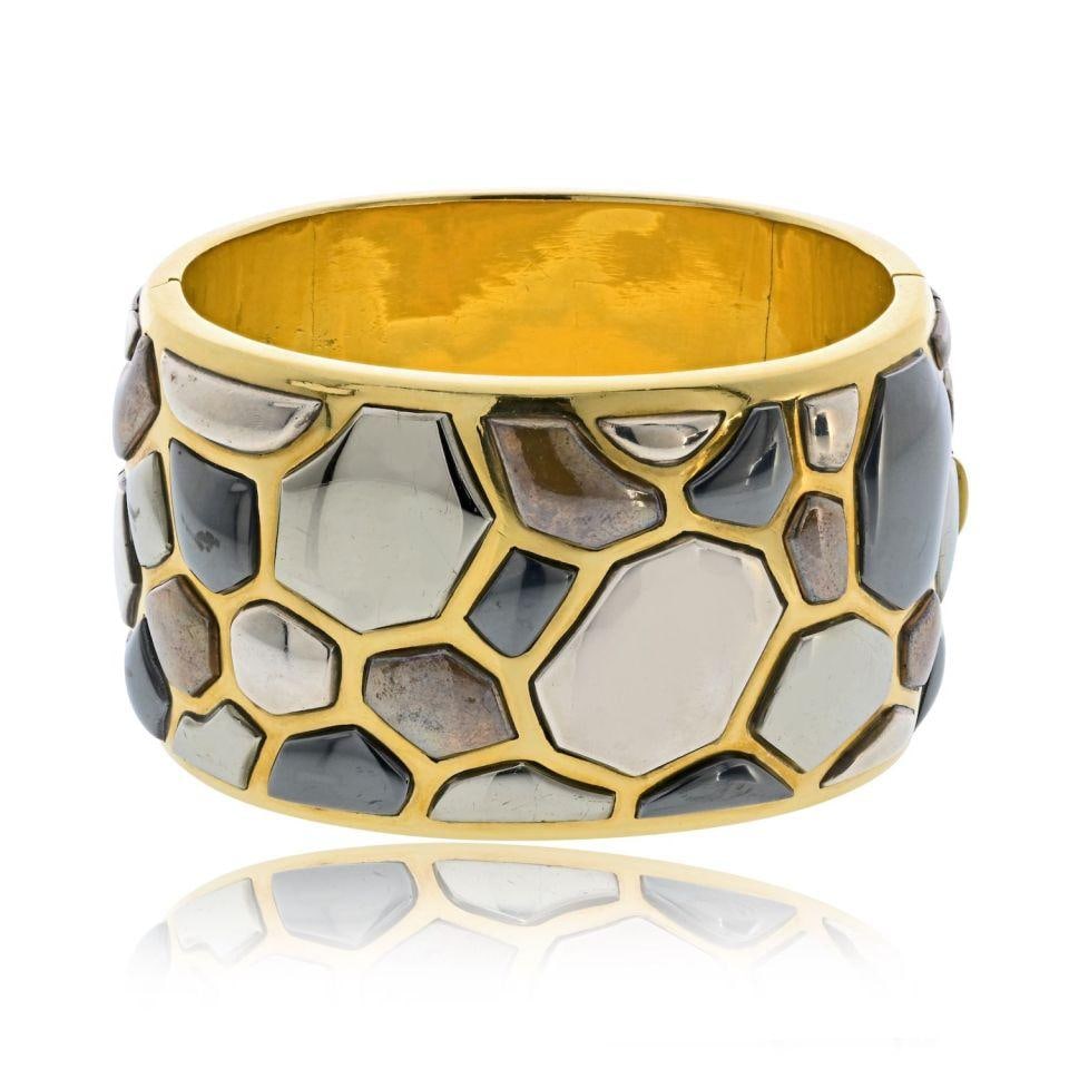 Angela Cummings 1981 Silver Inlay 18K Gold Bangle by Tiffany & Co.: Angela Cummings 1981 Silver Inlay 18K Gold Bangle by Tiffany & Co. This bold and sculptural bangle bracelet by Tiffany & Co., designed by Angela Cummings in 1981, is crafted from 18K yellow gold and f