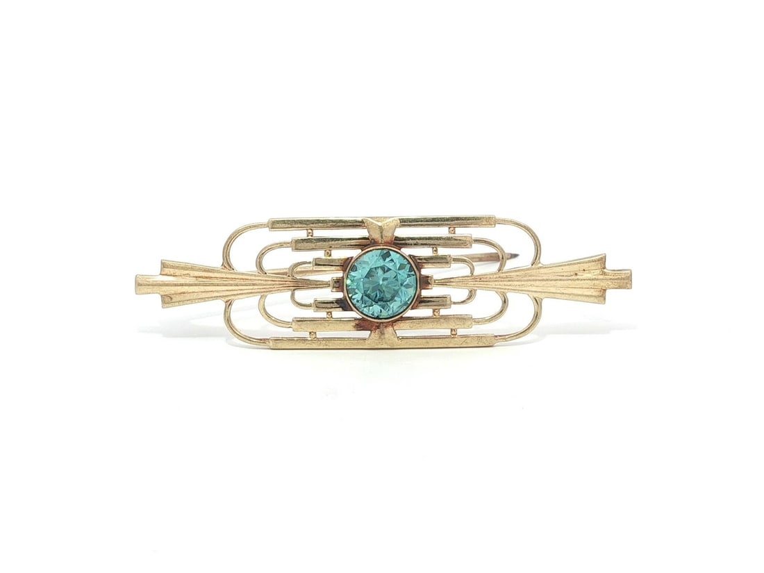 Blue Zircon Antique Brooch in 10k Yellow Gold Openwork Design: Blue Zircon Antique Brooch in 10k Yellow Gold Openwork Design This antique brooch features a high-quality, natural round-cut blue zircon set in solid 10k yellow gold. The brilliant blue zircon is beze