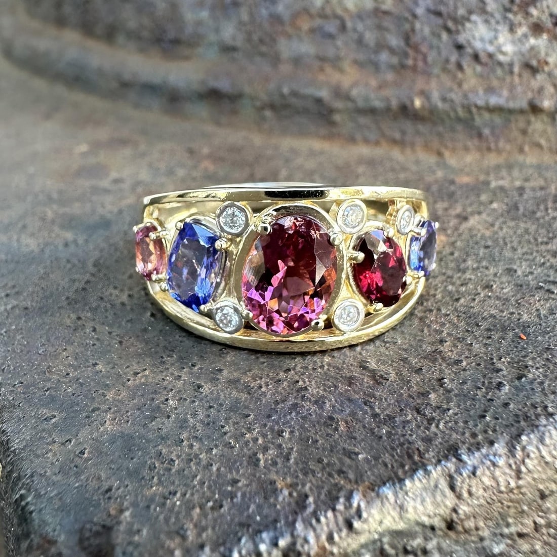 Colorful Wide Band Ring in 14k Yellow Gold with Tanzanite Garnet Tourmaline and Diamonds: Colorful Wide Band Ring in 14k Yellow Gold with Tanzanite Garnet Tourmaline and Diamonds This wide band ring features a vibrant combination of natural gemstones, including oval and cushion cut tourmal