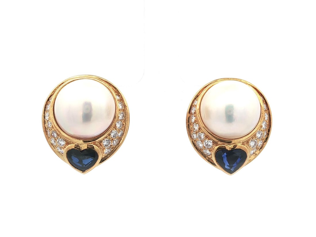 18k Gold Mabe Pearl Diamond Heart Sapphire Clip On Earrings: 18k Gold Mabe Pearl Diamond Heart Sapphire Clip On Earrings Elevate your style with these exquisite 18k Gold Mabe Pearl Clip-On Earrings featuring dazzling diamonds and heart-shaped sapphires. Each ea