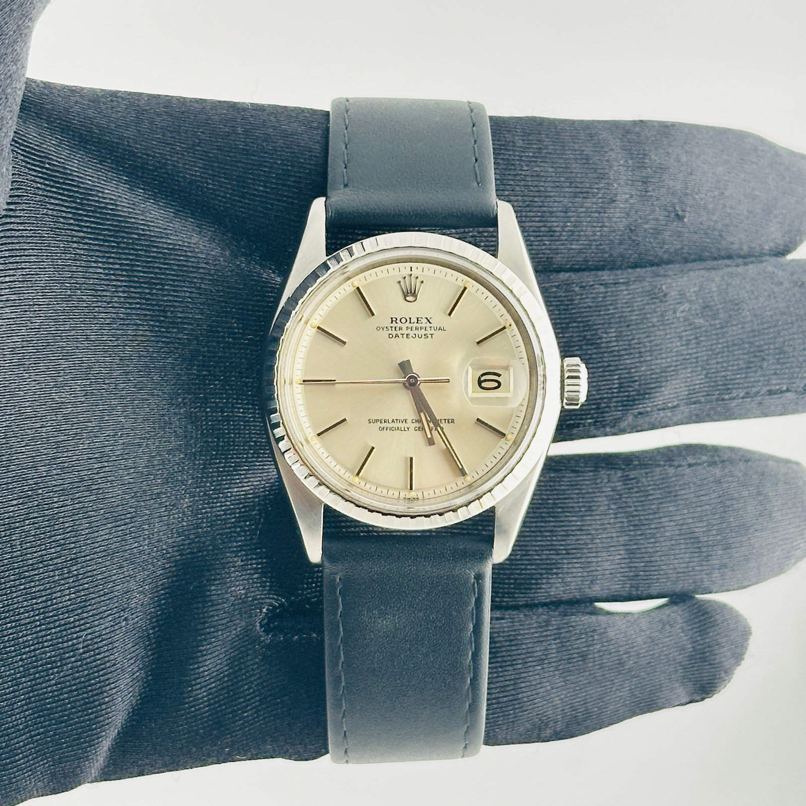 Rolex Datejust 1603 Silver Stick Dial Leather Band: Rolex Datejust 1603 Silver Stick Dial Leather Band This Rolex Datejust features a silver stick dial and an engine-turned bezel, complemented by a generic leather band. The watch is identified by refer
