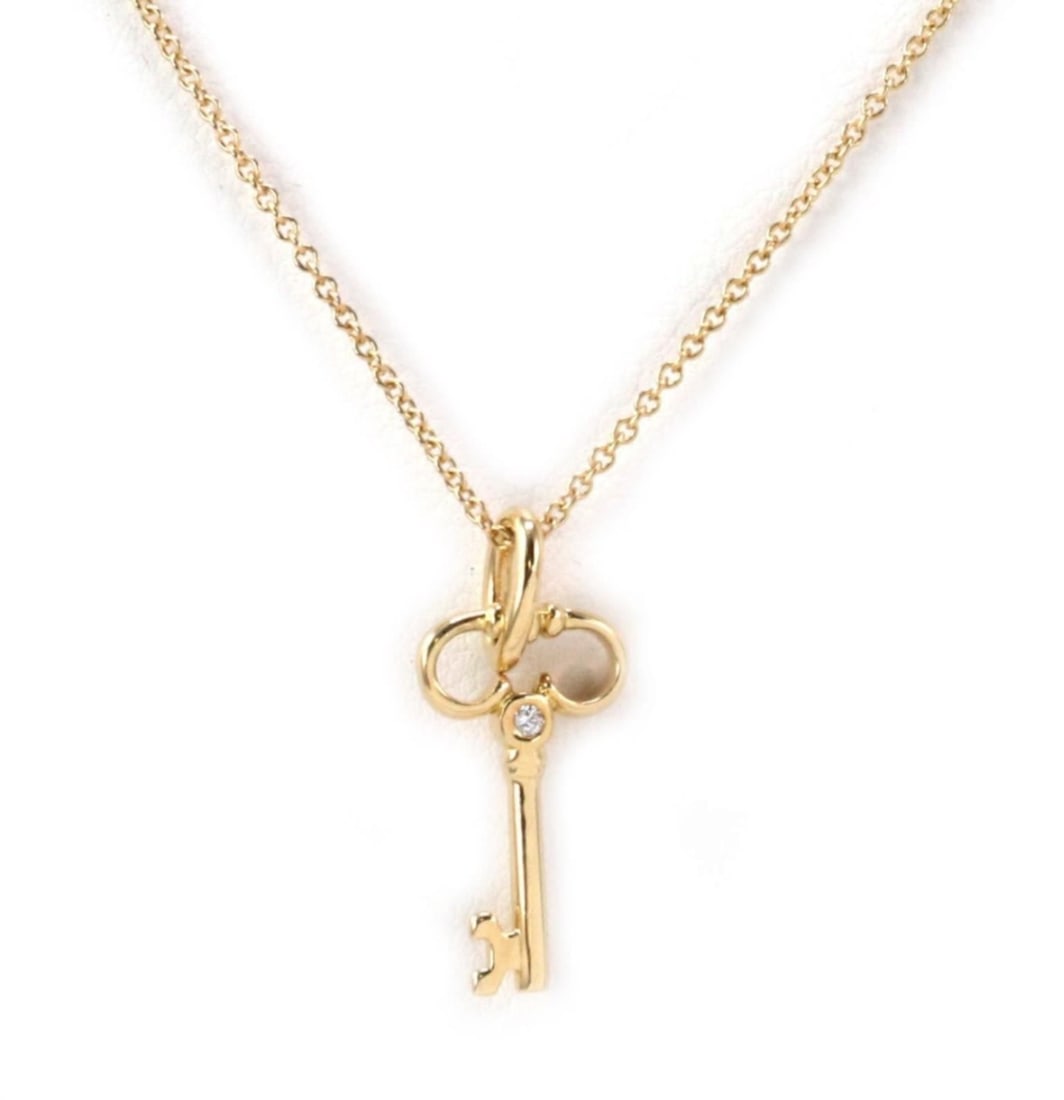 Tiffany & Co 18K Gold Diamond Key Pendant Necklace: Tiffany & Co 18K Gold Diamond Key Pendant Necklace This vintage Tiffany & Co. pendant necklace features a delicate key motif crafted in solid 18k yellow gold and accented with a single diamond. The pe