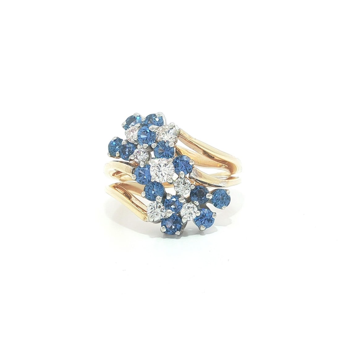 Yellow Gold Ring with Blue Sapphires and Diamonds in Floral Cluster Design: Yellow Gold Ring with Blue Sapphires and Diamonds in Floral Cluster Design This cocktail ring features a striking flower cluster design set in solid 14k yellow gold with a white gold top. The centerpi