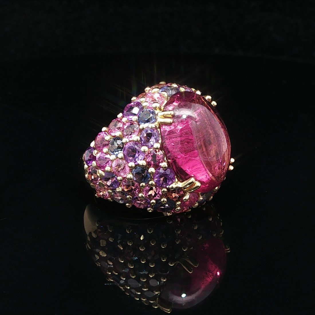 18k Yellow Gold Cocktail Ring with Vibrant Pink Purple Tourmaline: 18k Yellow Gold Cocktail Ring with Vibrant Pink Purple Tourmaline This stunning cocktail ring features a vibrant natural tourmaline as its centerpiece, highlighted by an array of colorful pink and pur
