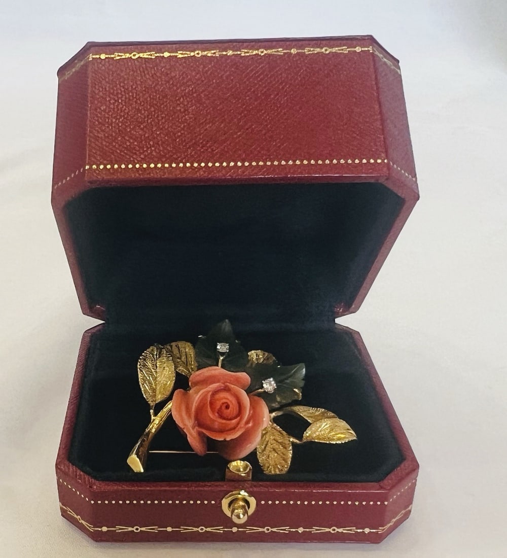 Cartier coral diamond 18k yellow gold brooch with box: Cartier coral diamond 18k yellow gold brooch with box This exquisite Cartier brooch showcases a sophisticated blend of 18k yellow gold, vibrant orange coral, nephrite, and approximately 0.15 carats of