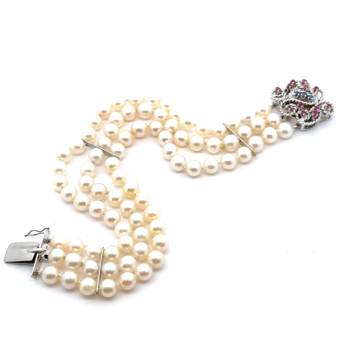 Vintage 18k White Gold Pearl Ruby Sapphire Floral Bracelet: Vintage 18k White Gold Pearl Ruby Sapphire Floral Bracelet This elegant vintage bracelet features a captivating three-strand design adorned with genuine cultured pearls, sapphires, and rubies. Crafted