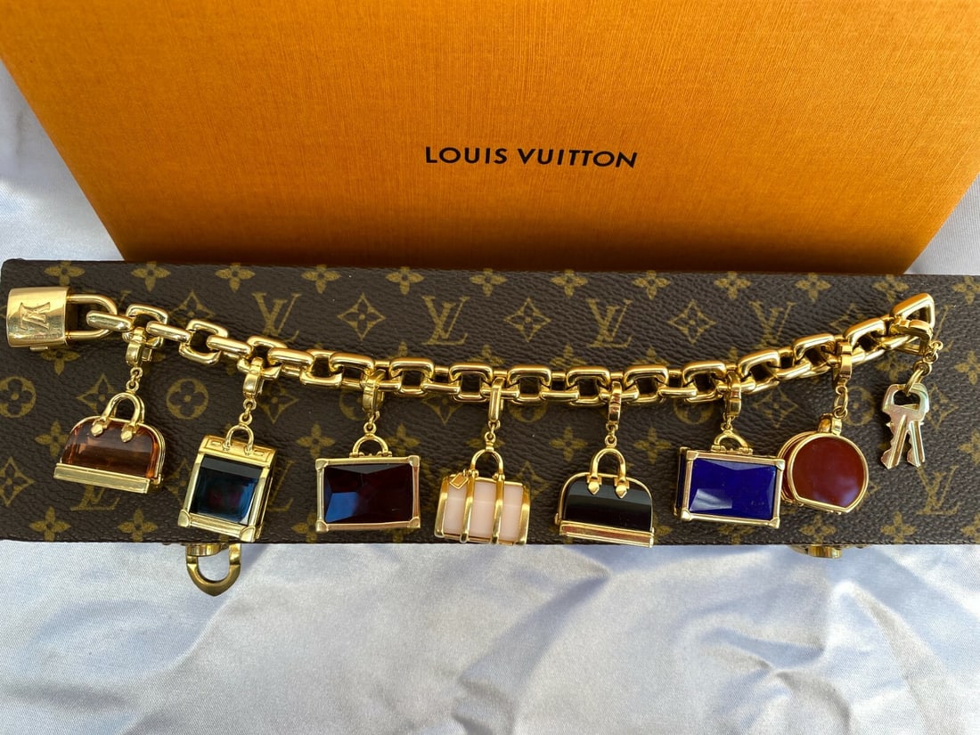 Louis Vuitton 18K Gold Charm Bracelet with 7 Gemstone Charms and Box: Louis Vuitton 18K Gold Charm Bracelet with 7 Gemstone Charms and Box This exquisite Louis Vuitton charm bracelet features a stunning design crafted from 18K yellow gold. It showcases seven unique hand