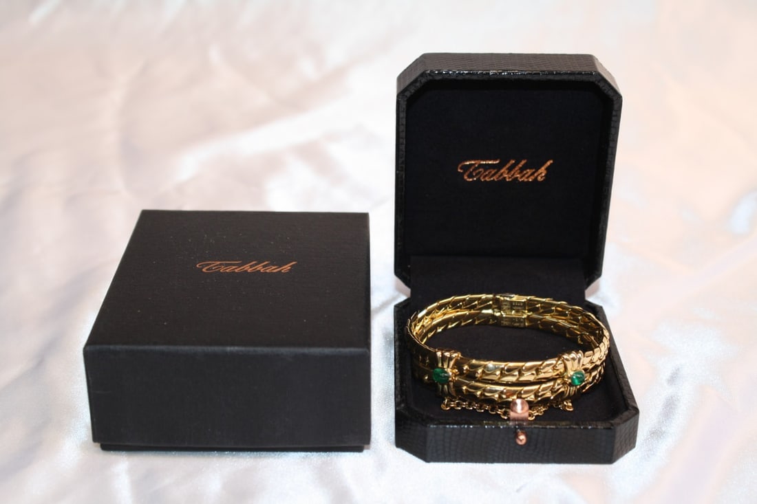 Tabbah 18K Gold Bangle Bracelet with Emeralds and Box: Tabbah 18K Gold Bangle Bracelet with Emeralds and Box This exquisite French bracelet by Tabbah showcases the elegance of 18K yellow gold, beautifully complemented by two cabochon emeralds weighing 1 c