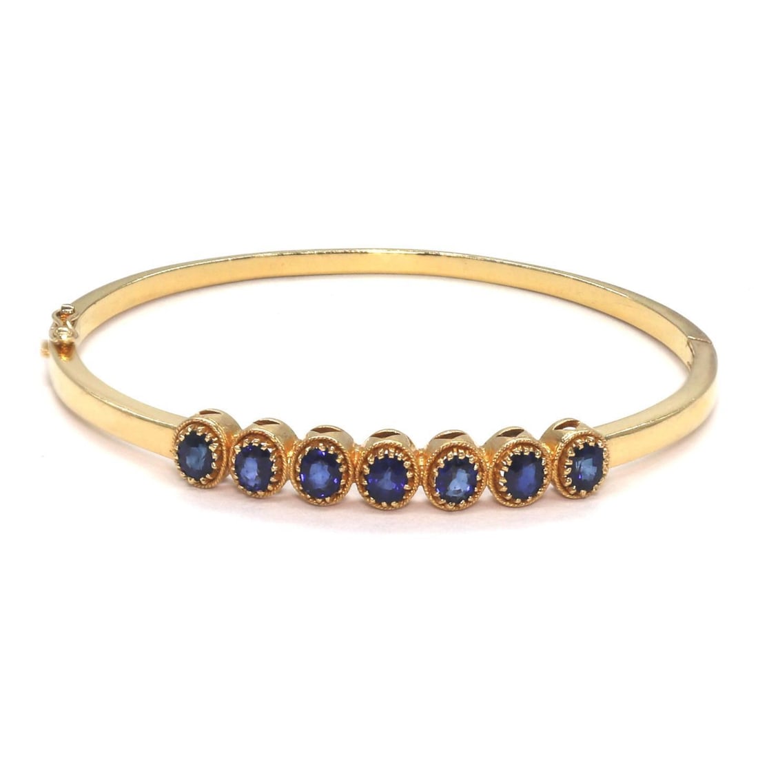 Elegant 22k Yellow Gold Bangle Bracelet with 7 Oval Blue Sapphires 3 Carat: Elegant 22k Yellow Gold Bangle Bracelet with 7 Oval Blue Sapphires 3 Carat This exquisite bangle bracelet features a hinged design with a secure push-in clasp. The front is adorned with 7 oval-cut blu