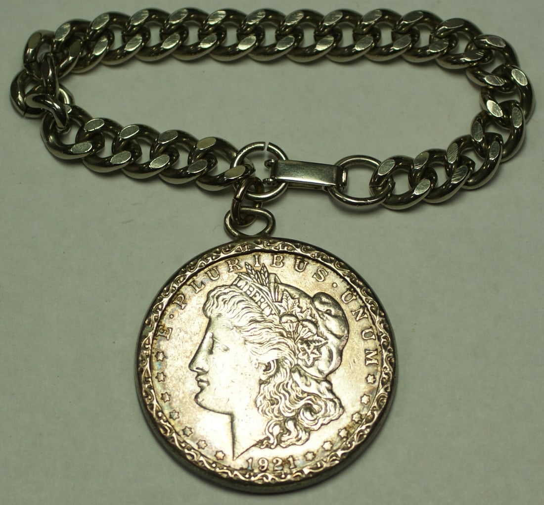 Bracelet Featuring 1921 Morgan Dollar in Engraved Silver Bezel: Bracelet Featuring 1921 Morgan Dollar in Engraved Silver Bezel This bracelet showcases a lightly toned 1921 Morgan Silver Dollar, set in an engraved silver bezel. The bezel features the initials "BMB"