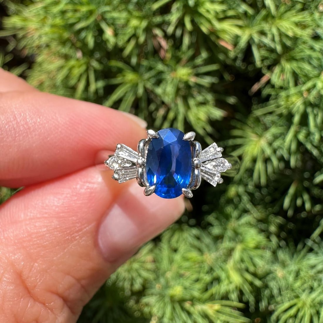 Platinum Cocktail Ring with Oval Blue Sapphire and Diamond Shoulders: Platinum Cocktail Ring with Oval Blue Sapphire and Diamond Shoulders Classic cocktail ring featuring an oval natural blue sapphire accented by baguette and round natural diamonds on the shoulders. Cra