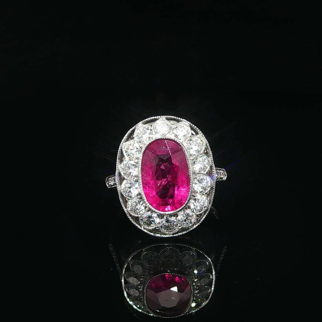 18k White Gold Ring With Pink Tourmaline and Diamond Halo Milgrain Detailing: 18k White Gold Ring With Pink Tourmaline and Diamond Halo Milgrain Detailing This women's cocktail ring features an elongated oval vivid pink tourmaline, bezel set and surrounded by a halo of round br
