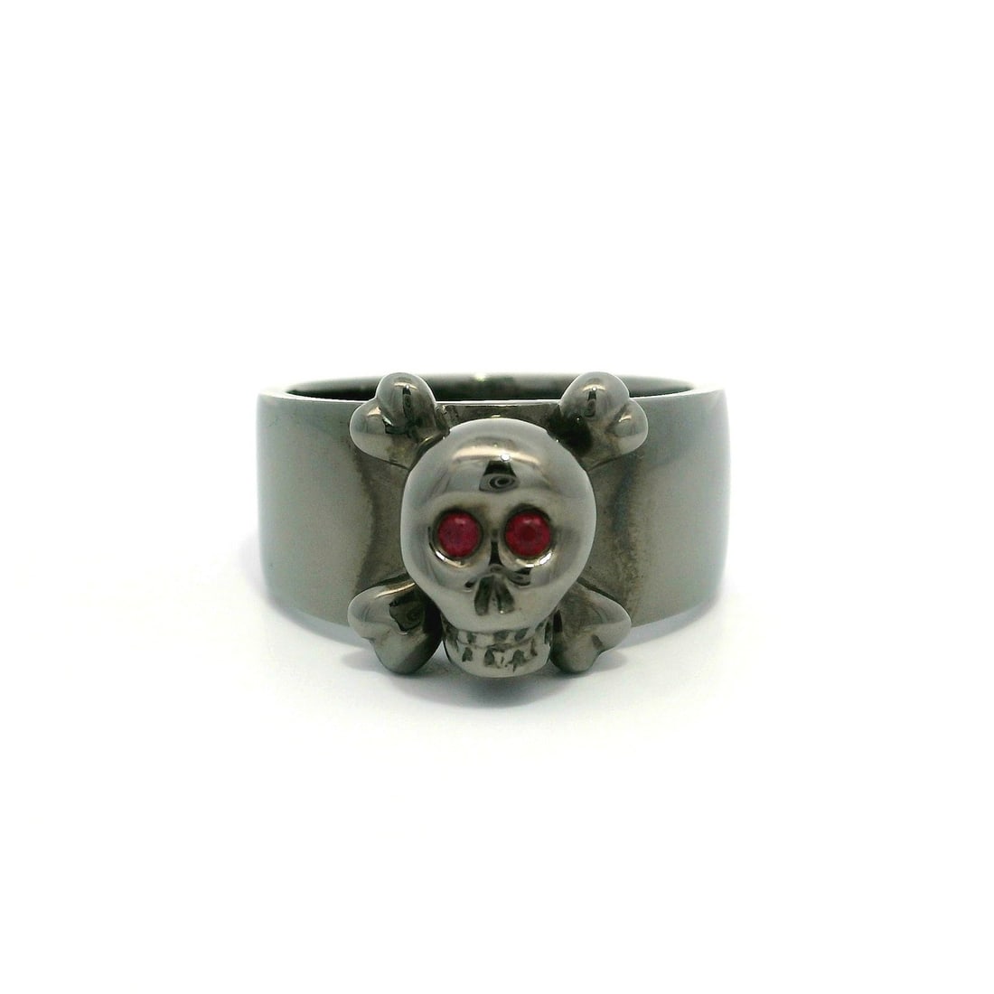 18k Blackened Gold Skull Ring with Ruby Eyes and Bone Design: 18k Blackened Gold Skull Ring with Ruby Eyes and Bone Design This striking wide band ring is crafted from solid 18k blackened gold, featuring a unique skull head design adorned with two natural genuin
