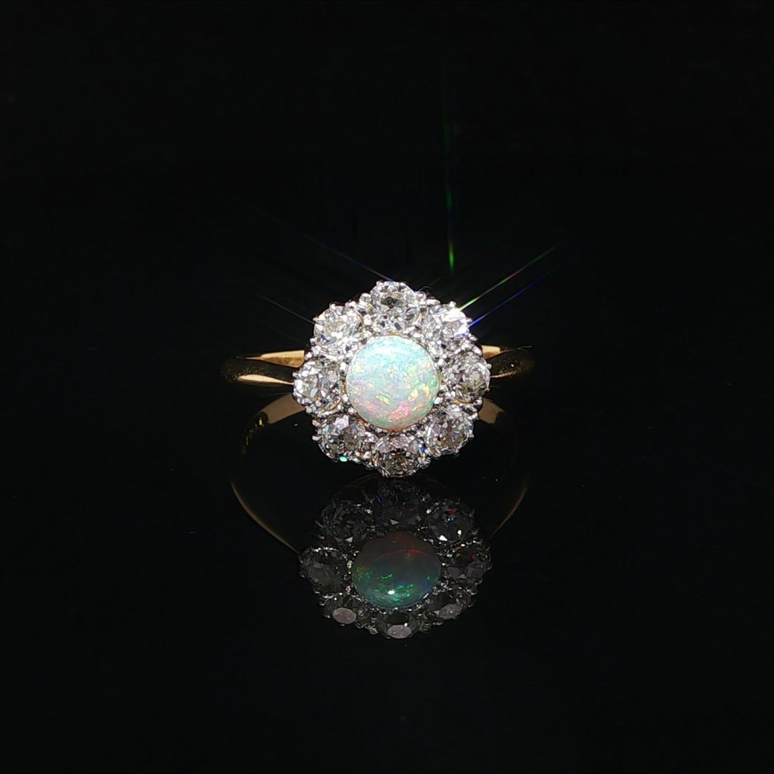 Edwardian 18k Gold Platinum Opal Diamond Halo Cluster Ring: Edwardian 18k Gold Platinum Opal Diamond Halo Cluster Ring This exquisite Antique Edwardian ring features an elegant cluster design, showcasing a stunning natural opal at its center. The opal is a rou