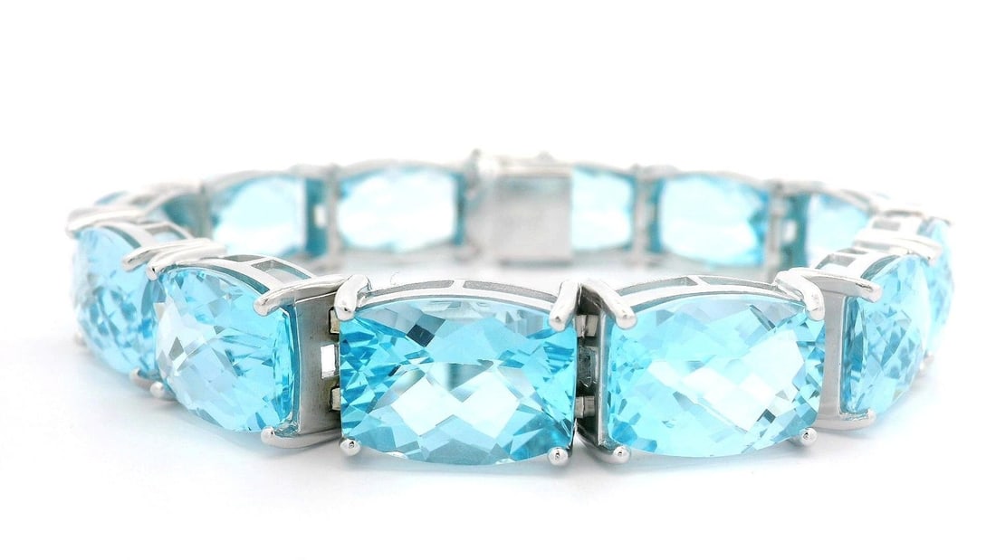 14k White Gold Large Blue Topaz Line Bracelet 112.80ctw: 14k White Gold Large Blue Topaz Line Bracelet 112.80ctw This stunning line bracelet features twelve natural genuine blue topaz stones, each fashioned in a rectangular cushion cut and prong-set to show