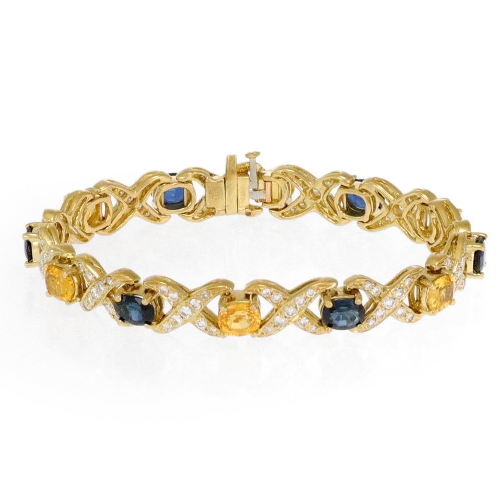 18k Yellow Gold Diamond Sapphire X Link Bracelet 8mm Wide: 18k Yellow Gold Diamond Sapphire X Link Bracelet 8mm Wide This exquisite bracelet is crafted from 18k yellow gold and features a stunning design of alternating X and oval shape links. The X links are 