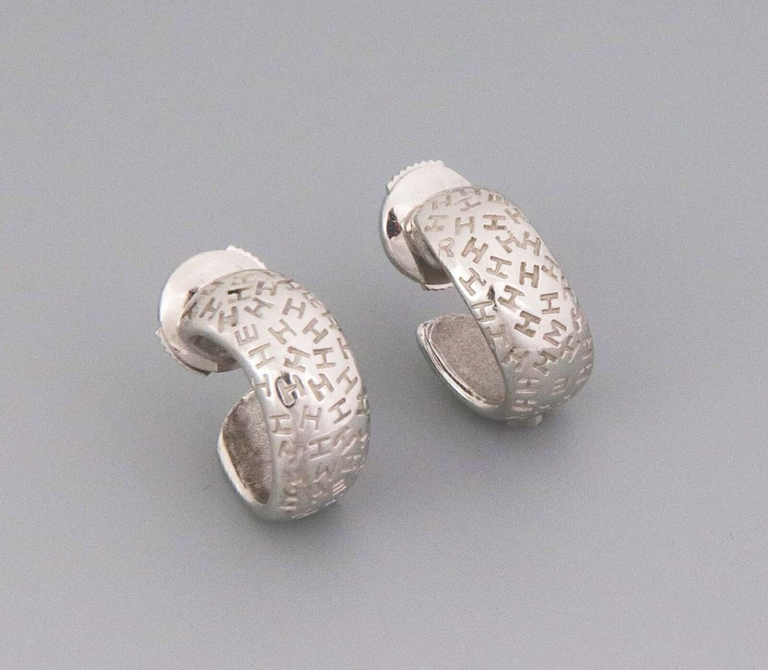 Hermes Graffiti 18k White Gold Huggie Hoop Earrings Pair: Hermes Graffiti 18k White Gold Huggie Hoop Earrings Pair A pair of Hermes Graffiti huggie hoop earrings crafted in 18k white gold. The design features a bold curved hoop silhouette with a wide polishe