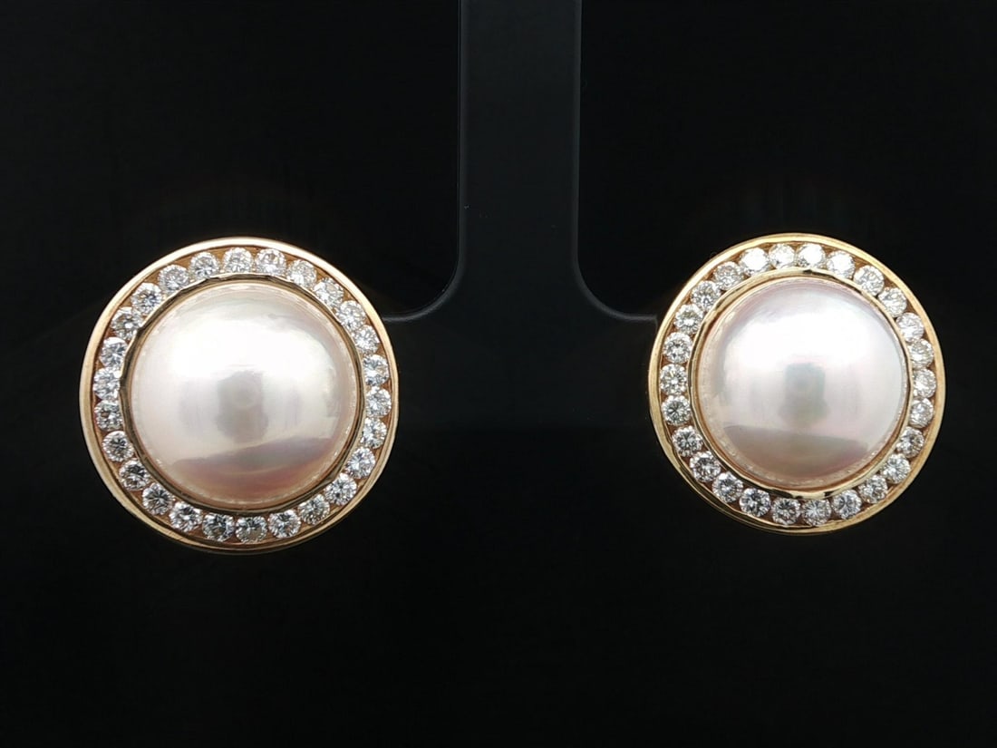 Omega 18K Yellow Gold 14mm Mabe Pearl Diamond Button Earrings: Omega 18K Yellow Gold 14mm Mabe Pearl Diamond Button Earrings Elevate your elegance with these stunning 18k Yellow Gold button earrings featuring exquisite 14mm Mabe pearls and dazzling diamonds. Each