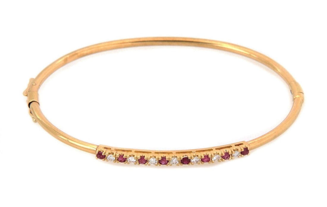 14k Yellow Gold Hinged Bangle Bracelet with Ruby and Diamond Accents: 14k Yellow Gold Hinged Bangle Bracelet with Ruby and Diamond Accents Estate-style hinged bangle bracelet crafted in 14k yellow gold with alternating natural ruby and diamond accents across the top. Th