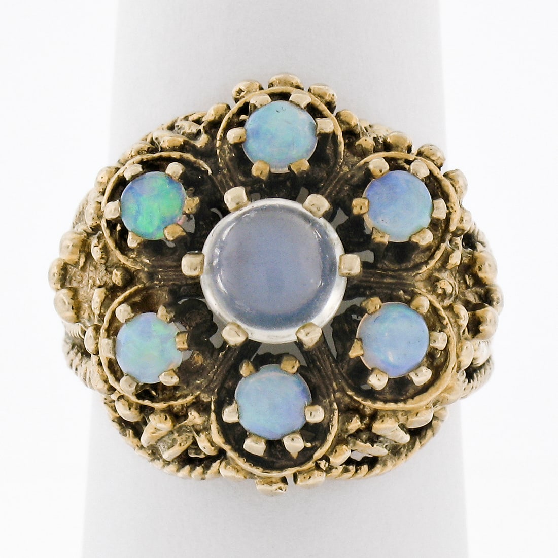 Vintage 14K Yellow Gold Blue Moonstone Opal Cluster Ring: Vintage 14K Yellow Gold Blue Moonstone Opal Cluster Ring This stunning vintage cocktail ring is crafted from solid 14K yellow gold and features a captivating cluster of gemstones. At its center, a rou