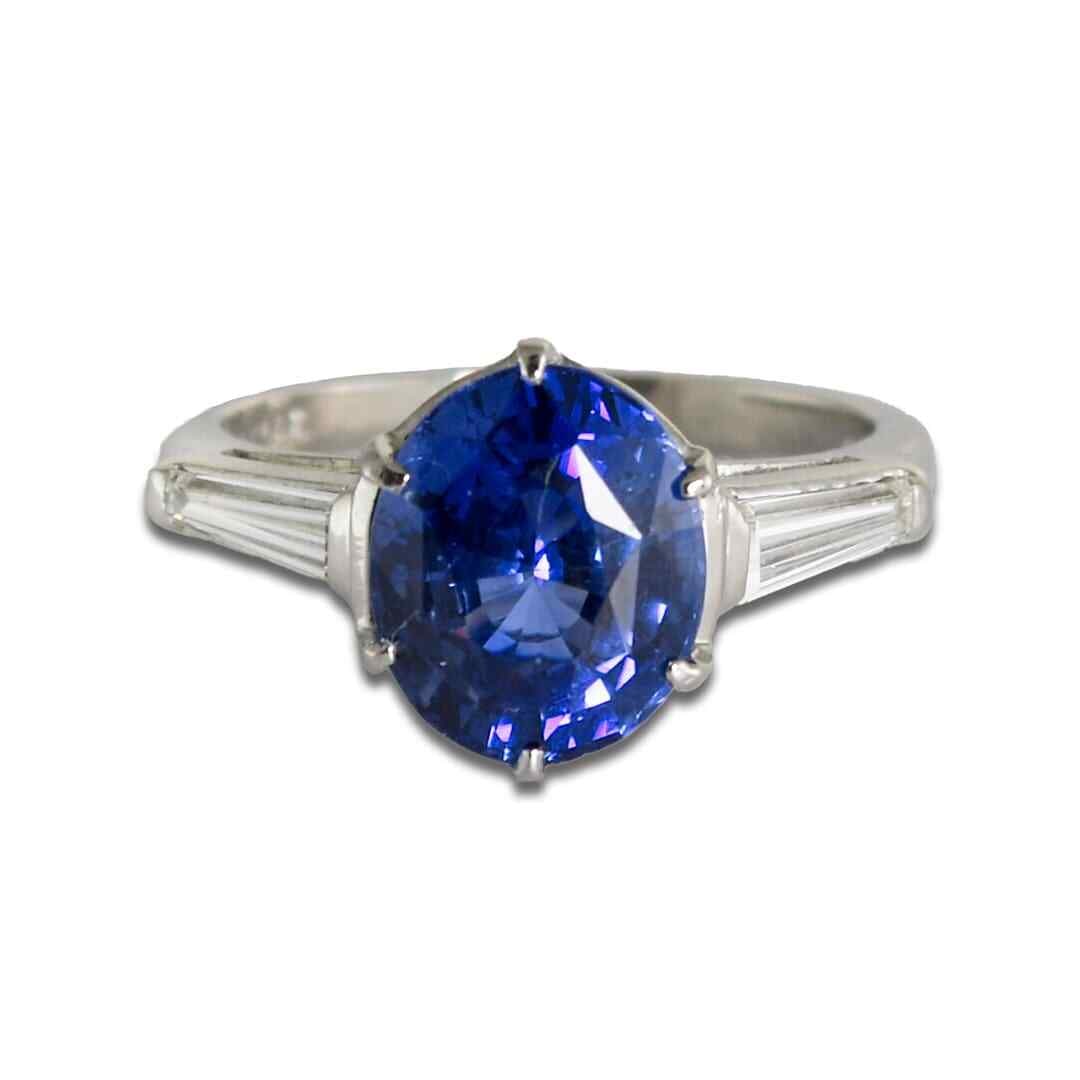 AGL Certified Platinum Cocktail Ring with 4.60ct Sapphire and 2 Diamonds: AGL Certified Platinum Cocktail Ring with 4.60ct Sapphire and 2 Diamonds Pre-owned cocktail ring featuring a natural oval Ceylon sapphire accented by two channel-set baguette diamonds. The sapphire is