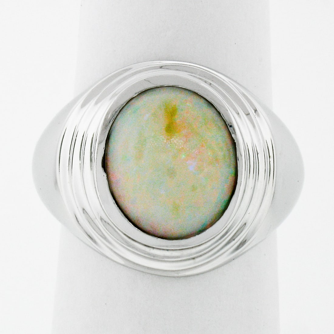 Vintage 14k White Gold Oval Opal Solitaire Dome Ring Unisex: Vintage 14k White Gold Oval Opal Solitaire Dome Ring Unisex This exquisite unisex vintage ring features a stunning natural opal set in a solid 14k white gold bezel. The oval cabochon-cut opal showcase