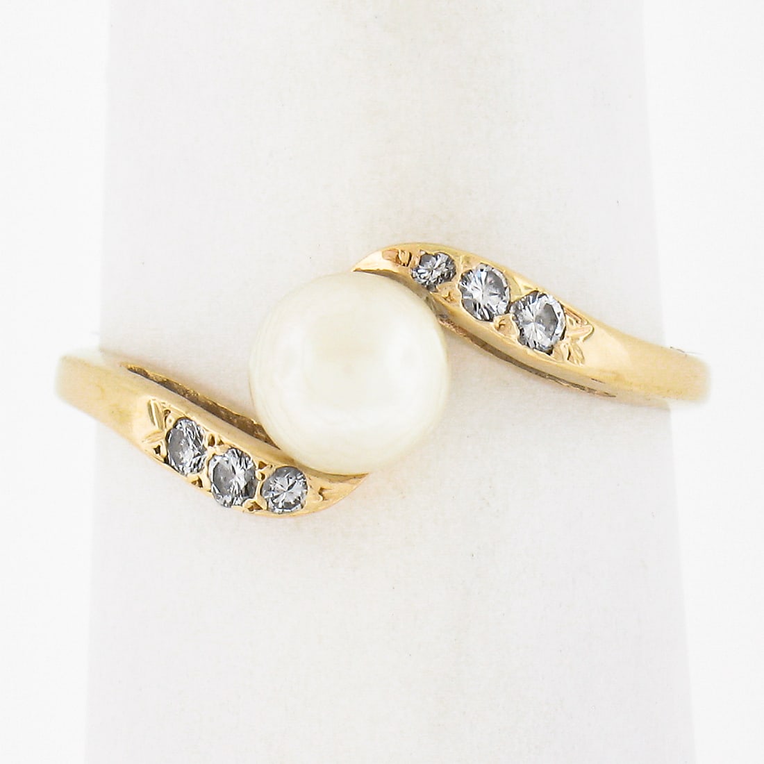 14K Yellow Gold Cultured Pearl and Diamond Bypass Ring 0.08ctw: 14K Yellow Gold Cultured Pearl and Diamond Bypass Ring 0.08ctw This exquisite 14K Yellow Gold ring features a stunning 5.5mm round cultured pearl set in a delicate solitaire design, complemented by a 