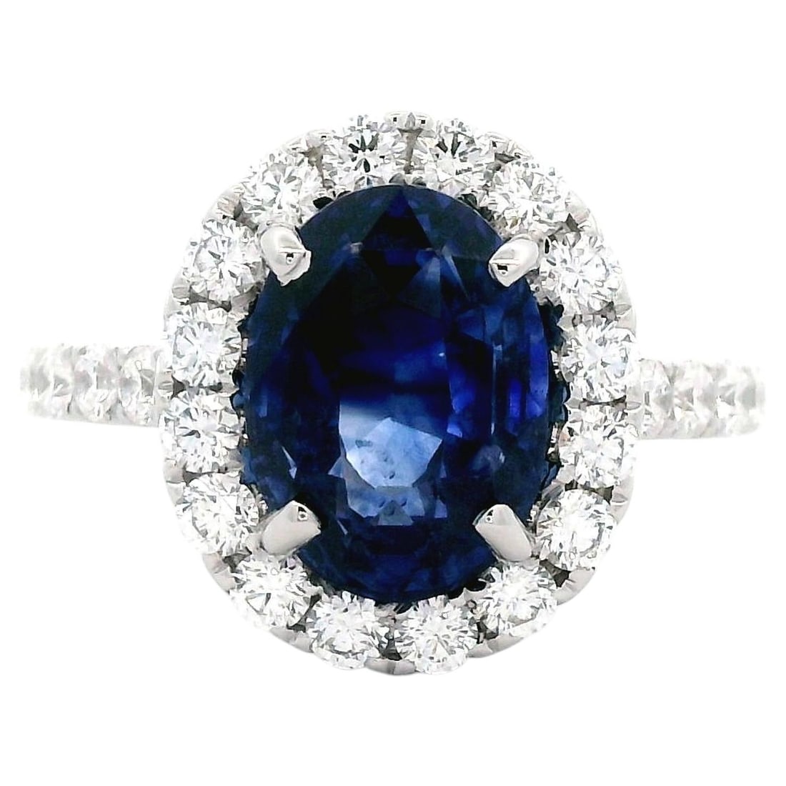 18k White Gold Ring with 5.02ct Ceylon Sapphire and Diamonds: 18k White Gold Ring with 5.02ct Ceylon Sapphire and Diamonds Contemporary ring featuring a GIA-certified 5.02 ct oval Ceylon blue sapphire accented by a halo of 28 round brilliant diamonds. Crafted in